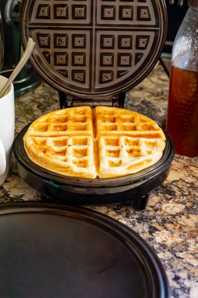 istock A finished waffle sits on the waffle iron with batter cup and honey in background. 2157336207