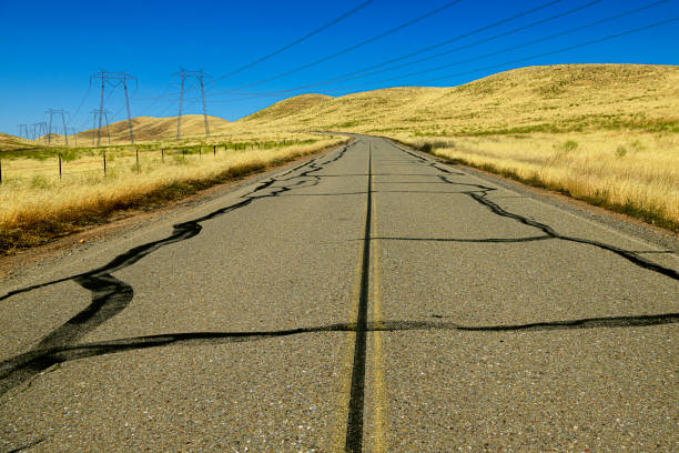 Rural country road winding it's way through the hills of the California coastal range hills, which are covered with dry grasses.  California is sometime known as the Golden State, because of the dry conditions that cause the wild vegetation to dry up.\n\nTaken near Los Banos, California, USA