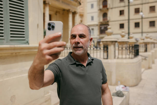 istock Mid-adult man taking a selfie with a smartphone in the city street 2157347330