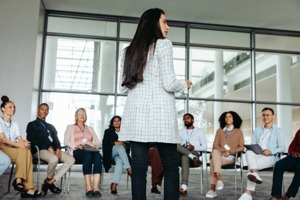 istock Female speaker leading a conference presentation for a diverse group of attendees 2157348165