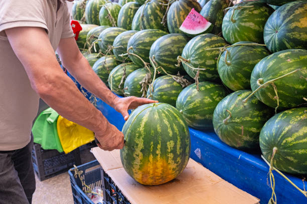 istock A watermelon seller cuts a watermelon at the market stall. 2157349021
