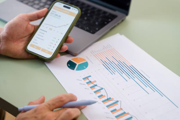istock Businessman analyzing financial charts and data on smartphone and documents 2157349502