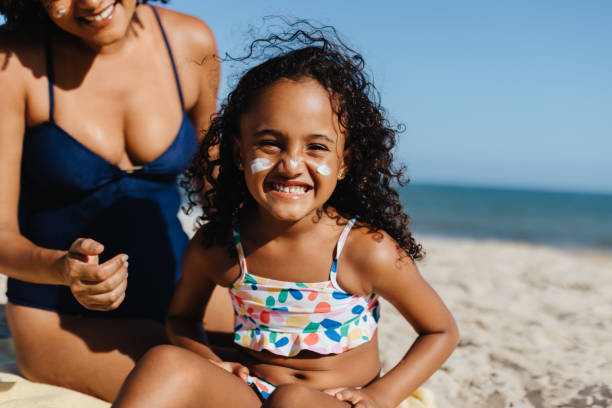 istock Happy girl applying sunscreen on the beach during a sunny summer day 2157349720