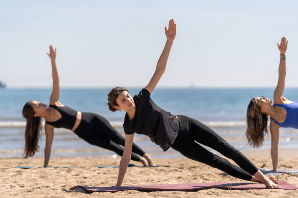 Women Practicing Side Plank Pilates on the Beach