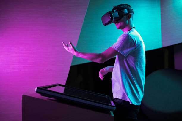 istock Young man in VR glasses standing making hand gestures in the air 2157353934