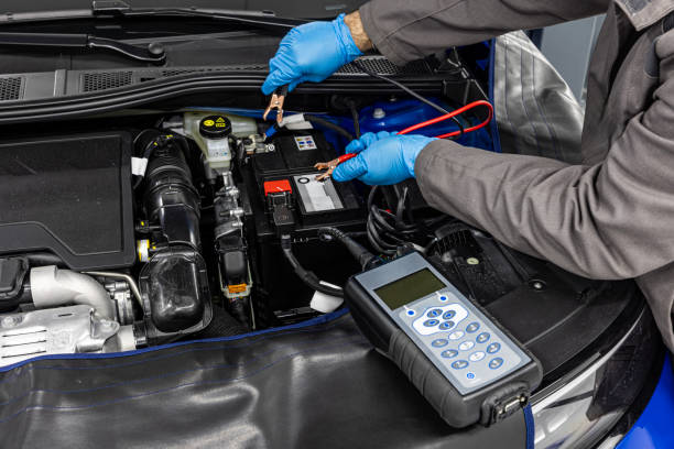 istock Car master mechanic checking and testing automotive battery with digital electronic battery tester and analyzer in auto vehicle workshop. 2157353991