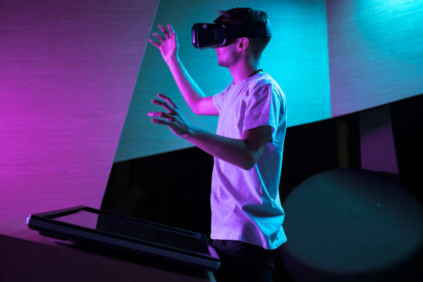 istock Young man in VR glasses standing making hand gestures in the air 2157354446