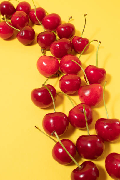 Colorful food pattern made of cherries on yellow background. Flat lay.
