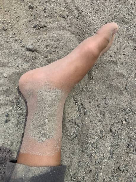 Person strolling along a serene beach, capturing peaceful moments. Close-up of feet with sandy toes.