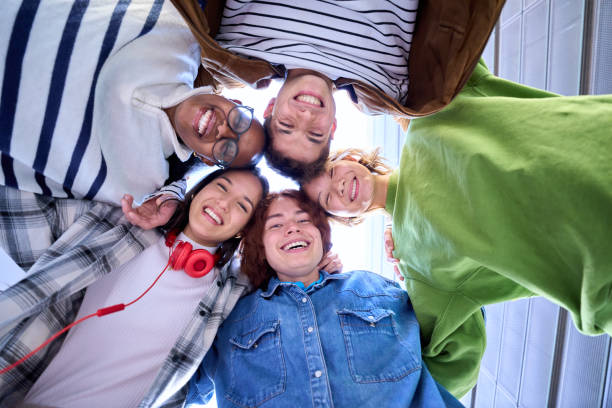 istock Low angle. Group of happy, smiling, multiracial classmates students gathered in circle stacking hand 2157360357