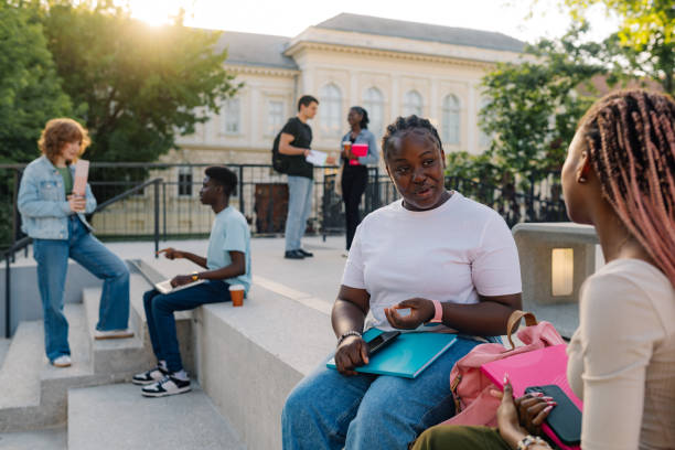 istock Diverse student girl on stairs at campus talking with classmate on break 2157364645