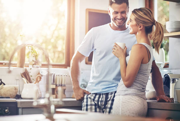 istock Smile, couple and drinking coffee in home kitchen for conversation, chat and morning. Tea, happy man and woman together for connection, love or laugh at funny joke for bonding with partner in house 2157365973