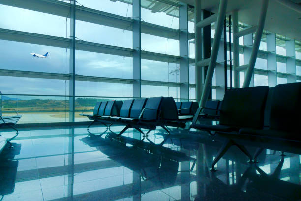 An empty airport departure area seats with a view from the windows of an airplane taking off