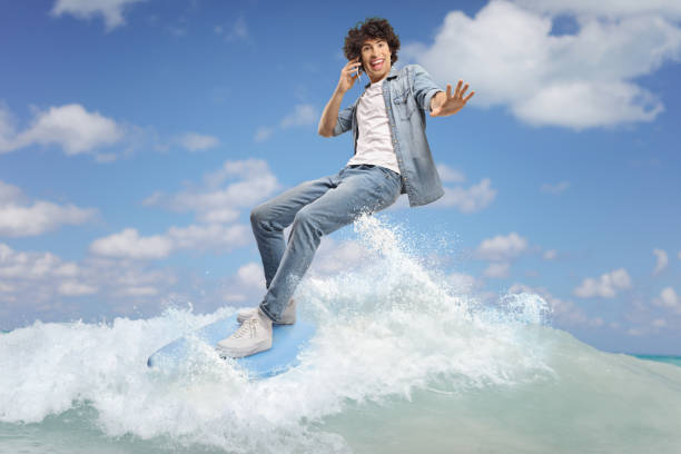 istock Man in jeans surfing on a surfboard and using a smartphone 2157370205