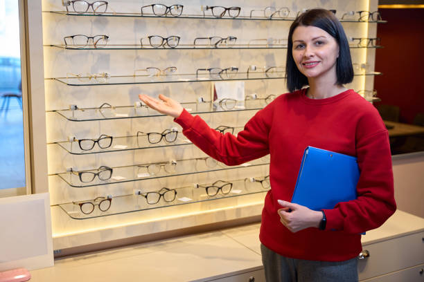 istock Woman in a red sweatshirt stands at a display case with glasses 2157371797