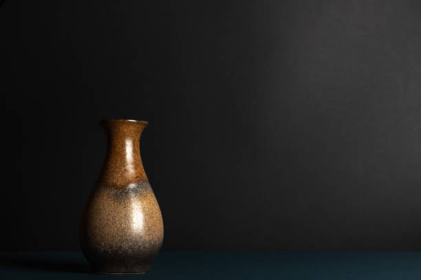 Empty vintage brown ceramic vase on a black background. Still life, plenty of space for text.