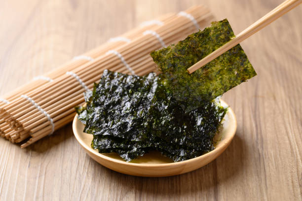 dried seaweed sheet on wooden plate with chopsticks, asian food ingredient - zeewier stockfoto's en -beelden
