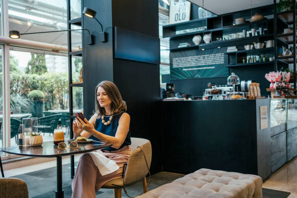 istock Businesswoman using cell phone in hotel cafe 2157374431