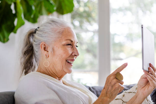 istock Elderly woman using a tablet on a couch 2157380432