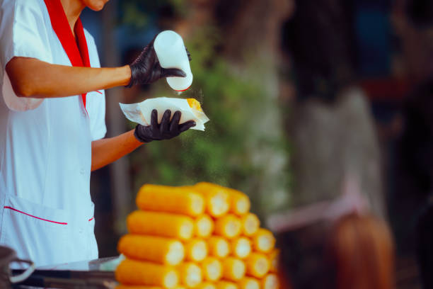 istock Street Vendor Adding Salt to Boiled Corn for Sale 2157380729