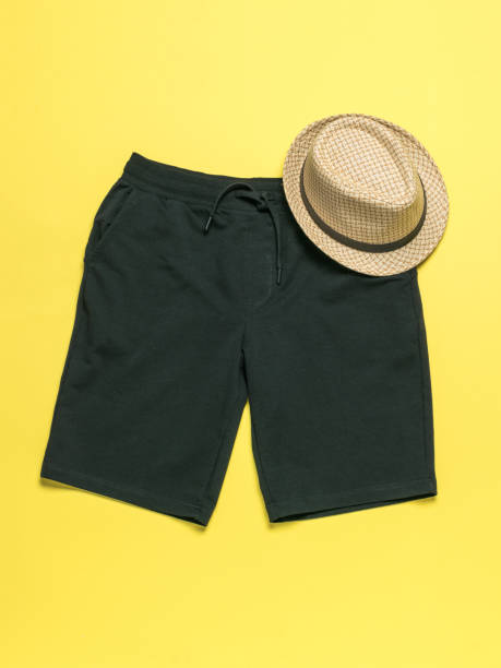 Casual Summer Outfit: Green Shorts and Straw Hat on Yellow Background for Easy Vacation Style