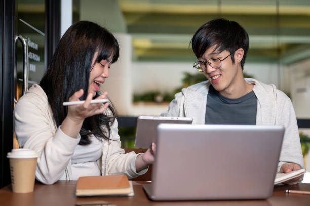 istock A young Asian female college student is explaining something on her digital tablet to her friend. 2157382512