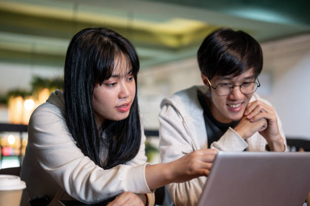 istock A smart Asian female student is helping her friend with a project, explaining something on a laptop. 2157382513
