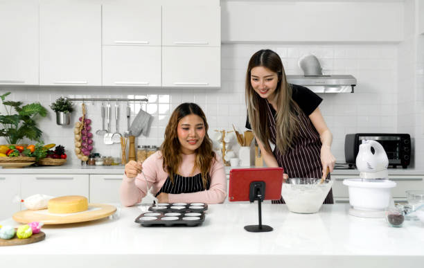 istock Two young women in an apron make dessert in the kitchen while looking at online recipe guide book on tablet computer. 2157385232