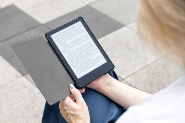 istock woman reading an e-book sitting on a park bench. 2157389428
