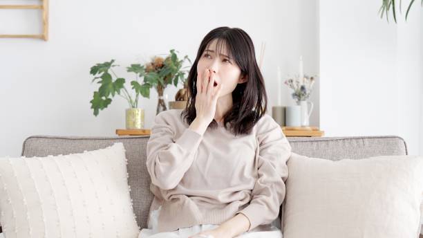 woman yawning in the living room - 不眠症 ストックフォトと画像