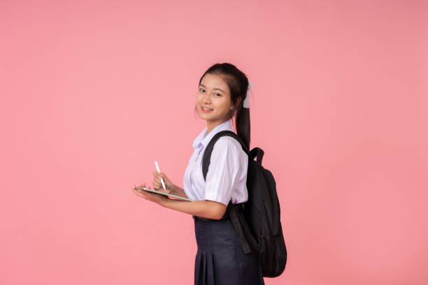 istock Asian female student with long hair Carrying a laptop computer bag, studying for knowledge, being a presenter at a tutoring institute, taking photos in a studio with a pink background. 2157392310