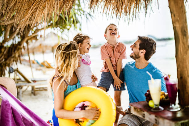 Happy parents having fun with their small kids in a beach bar.
