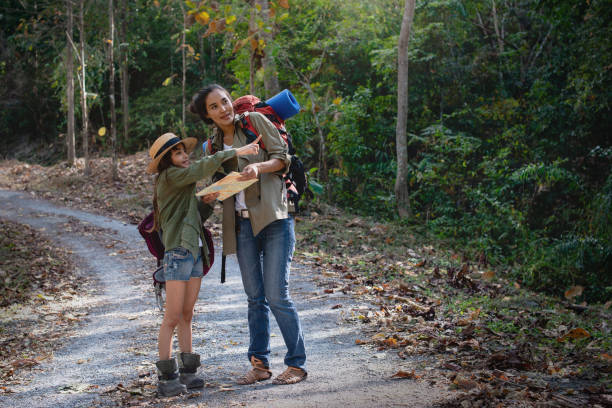 Mother and daughter discuss hiking routes on a map, child girl points to the target in front of her, adventure lifestyle outdoor concept
