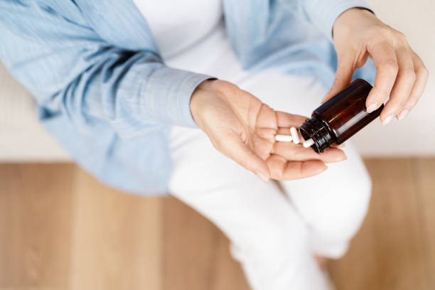 istock Woman Pouring White Capsules from Brown Bottle into Hand 2157397625