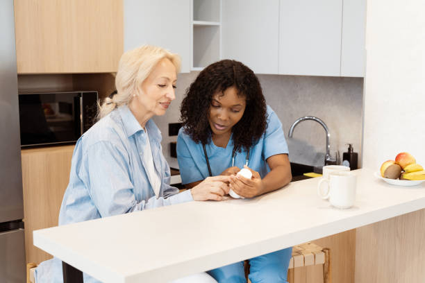 Nurse Assisting Elderly Woman with Medication at Home Kitchen