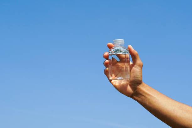 istock hand holding a drink water plastics bottle with blue sky backgrounds. 2157399517