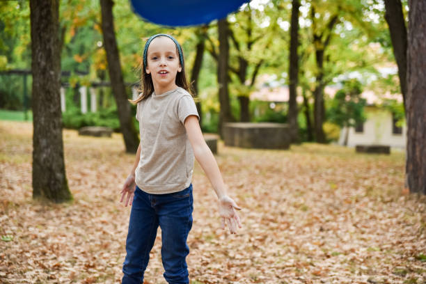 Cute little girl having fun while throwing disc in autumn park