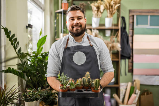 istock Young florist is holding cactuses looking at camera 2157402195