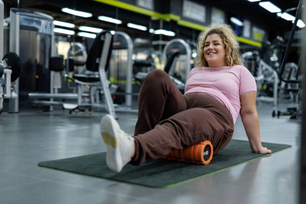 istock Smiling woman using a foam roller at gym 2157402267