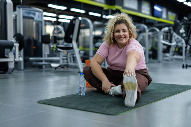 istock Plus-size woman stretching at gym 2157402378
