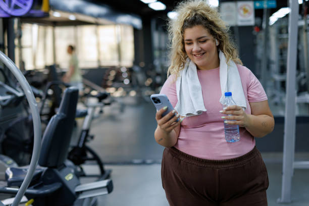 istock Cheerful Young Woman Browsing Phone in Gym 2157402425