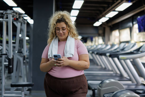 istock Plus Size Woman Using Phone at Gym 2157402439