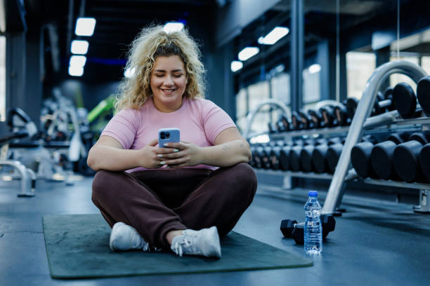 istock Happy Plus Size Woman Texting in Gym 2157402684