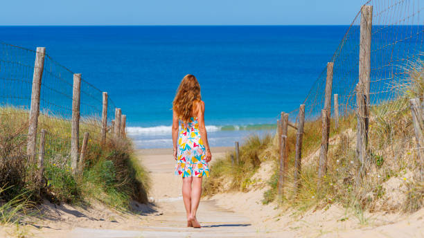 istock Woman at seaside, sand dune on the beach 2157402814