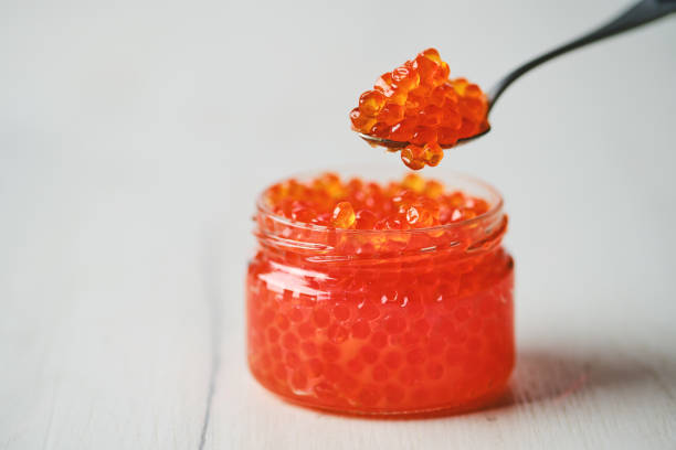 Open jar with red caviar and a spoon above it