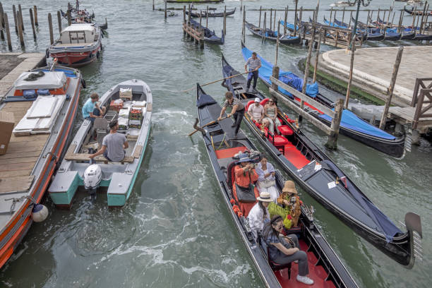 Venice, Italy - June 7th 2024: Gondolas with tourists and motorboats in a narrow channel in the center of the the old town of Venezia