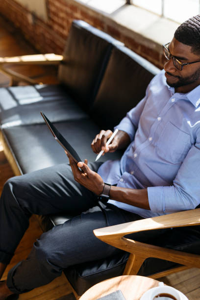 istock Black man using a stylus with a digital tablet on a couch social template 2157407625