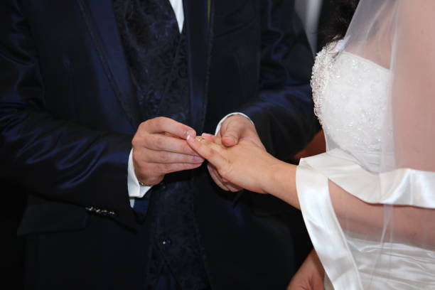 istock Groom in a blue suit is putting a wedding ring on a bride's finger during a wedding ceremony 2157417935