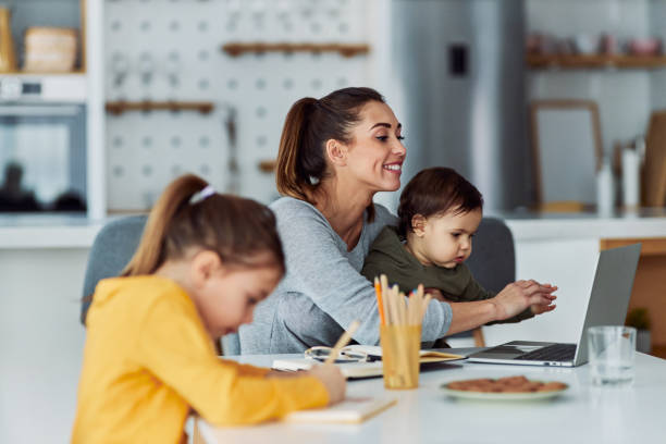 A happy mother watching over her two children while working at home using her laptop