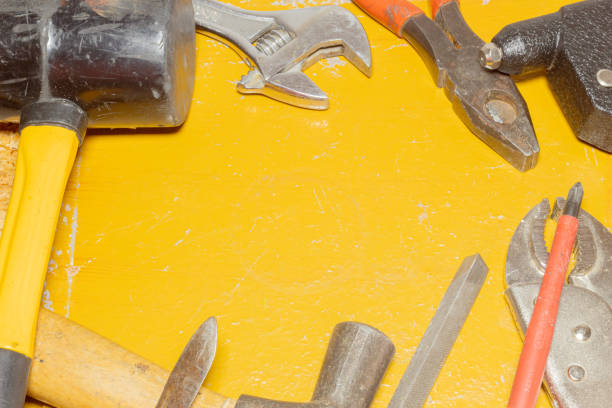 Kit of old working tools on a weathered yellow wooden background. Image with copy space.